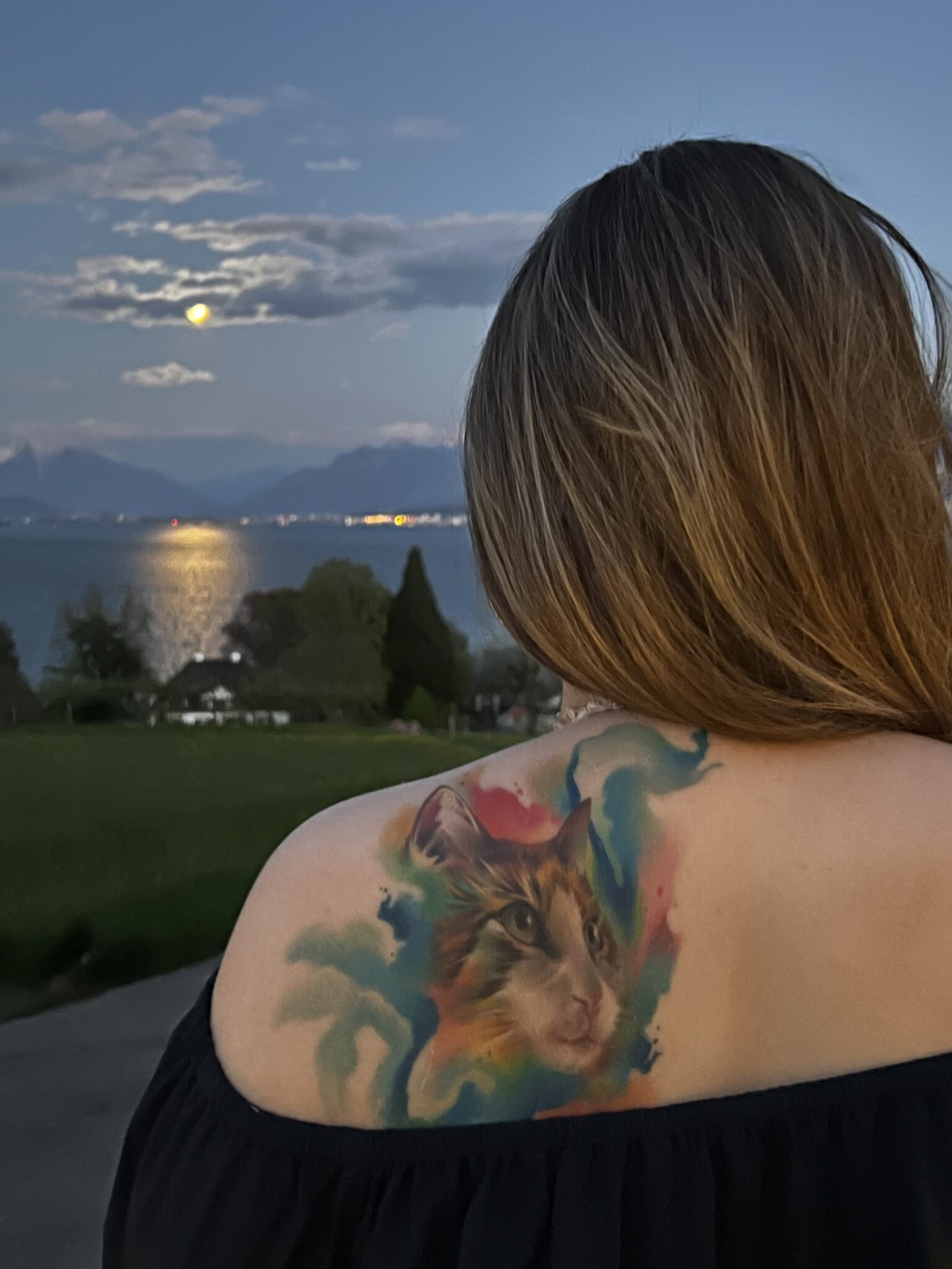 Junge selbstbewusste Frau, die in ihre Zukunft blickt. Wunderbares Tattoo auf der linken Schulter von ihrer Katze und zwar in Farbe!